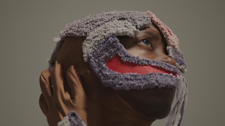 Das Foto zeigt den teilverhüllten Kopf der Künstlerin Edith Saldanha. Sie blickt nach oben rechts.